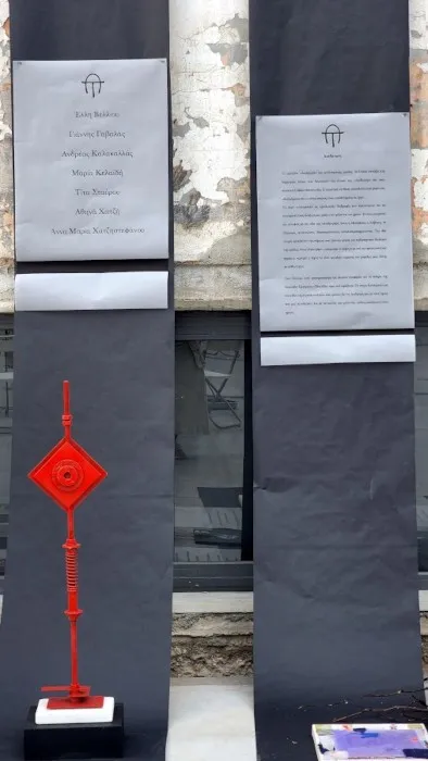 Άποψη από την εγκατάσταση «Διαδρομές»: χάρτινοι διάδρομοι σε μαύρο και γκρι στρωμένοι στο δάπεδο βιομηχανικού χώρου, με τα έργα των καλλιτεχνών και τυπωμένους στίχους τοποθετημένους πάνω τους.