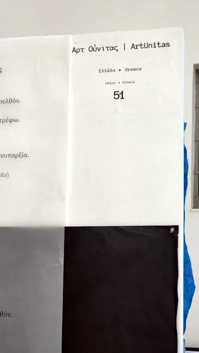 Άποψη από την εγκατάσταση «Διαδρομές»: χάρτινοι διάδρομοι σε μαύρο και γκρι στρωμένοι στο δάπεδο βιομηχανικού χώρου, με τα έργα των καλλιτεχνών και τυπωμένους στίχους τοποθετημένους πάνω τους.